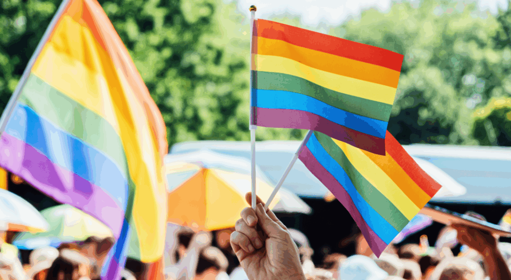 Pride flags waving at a gathering during Pride Month.